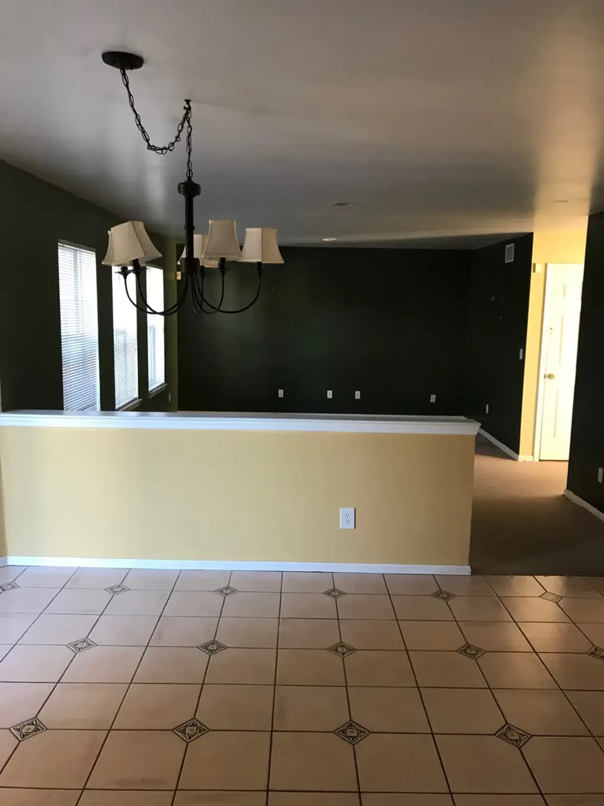 Selling a house as-is in Commack: empty open dining area with a chandelier and a half wall